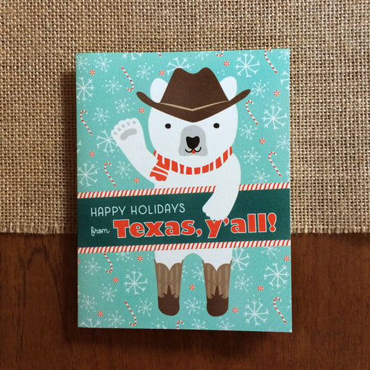 Polar Texas folded paper holiday card featuring a polar bear in a cowboy hat, red striped scarf and cowboy boots waving against an aqua background with snowflakes and candy canes and the greeting "Happy Holidays from Texas, y'all!"