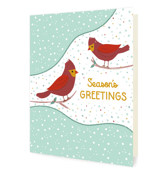 Cardinal Greetings folded paper holiday card featuring two red cardinals perched on branches against a soft mint and white snow-dotted winter background with the greeting "Season's Greetings"