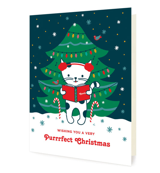 Caroling Kitty folded paper holiday card featuring a white cat in red earmuffs holding a carol book in front of a decorated Christmas tree with colorful lights, with the greeting "Wishing you a Very Purrrfect Christmas"