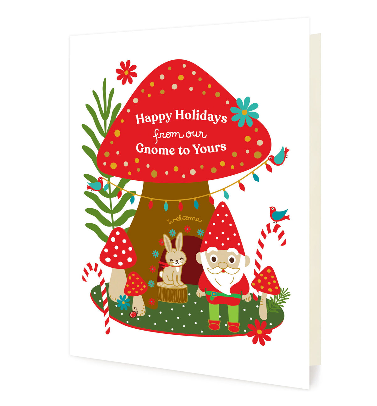 Gnome Home folded paper holiday card featuring a gnome and a bunny beside a large red mushroom house decorated with string lights, candy canes and colorful flowers, with the greeting "Happy Holidays from our Gnome to Yours"