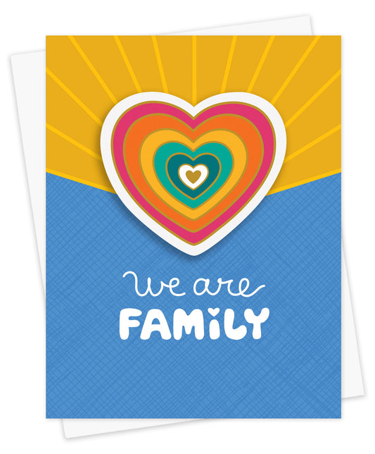 Sticker greeting card featuring a colorful blue and yellow background with a removable rainbow heart vinyl sticker and the message "We Are Family." Shown with a white envelope.