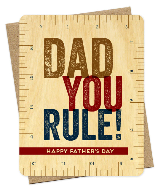 Wood Father's Day card featuring a ruler design and the message "Dad You Rule! Happy Father's Day." Shown with a kraft envelope.