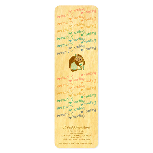 Back of birch wood bookmark featuring a sloth hugging a book surrounded by a pastel "I heart reading" text pattern. At the bottom: Night Owl Paper Goods script logo with text reading "Made in the USA - Eco-Friendly Sustainably Harvested Wood - Visit us at nightowlpapergoods.mom."